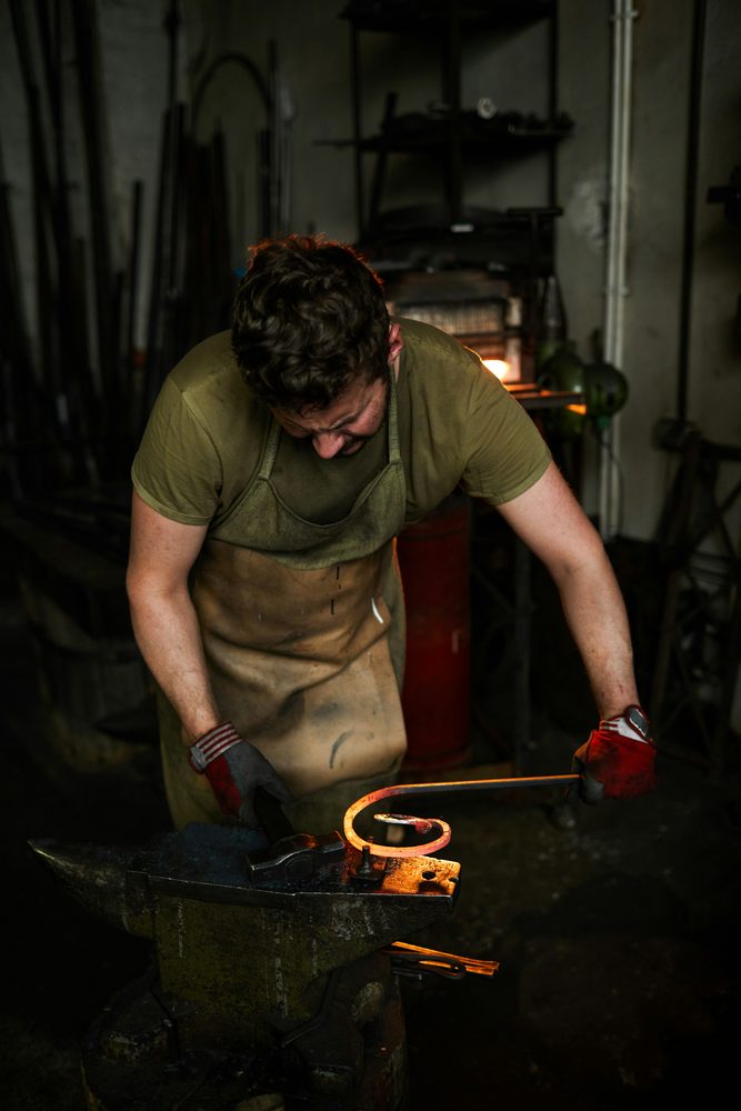 Blacksmith shaping a piece of hot iron on an anvil